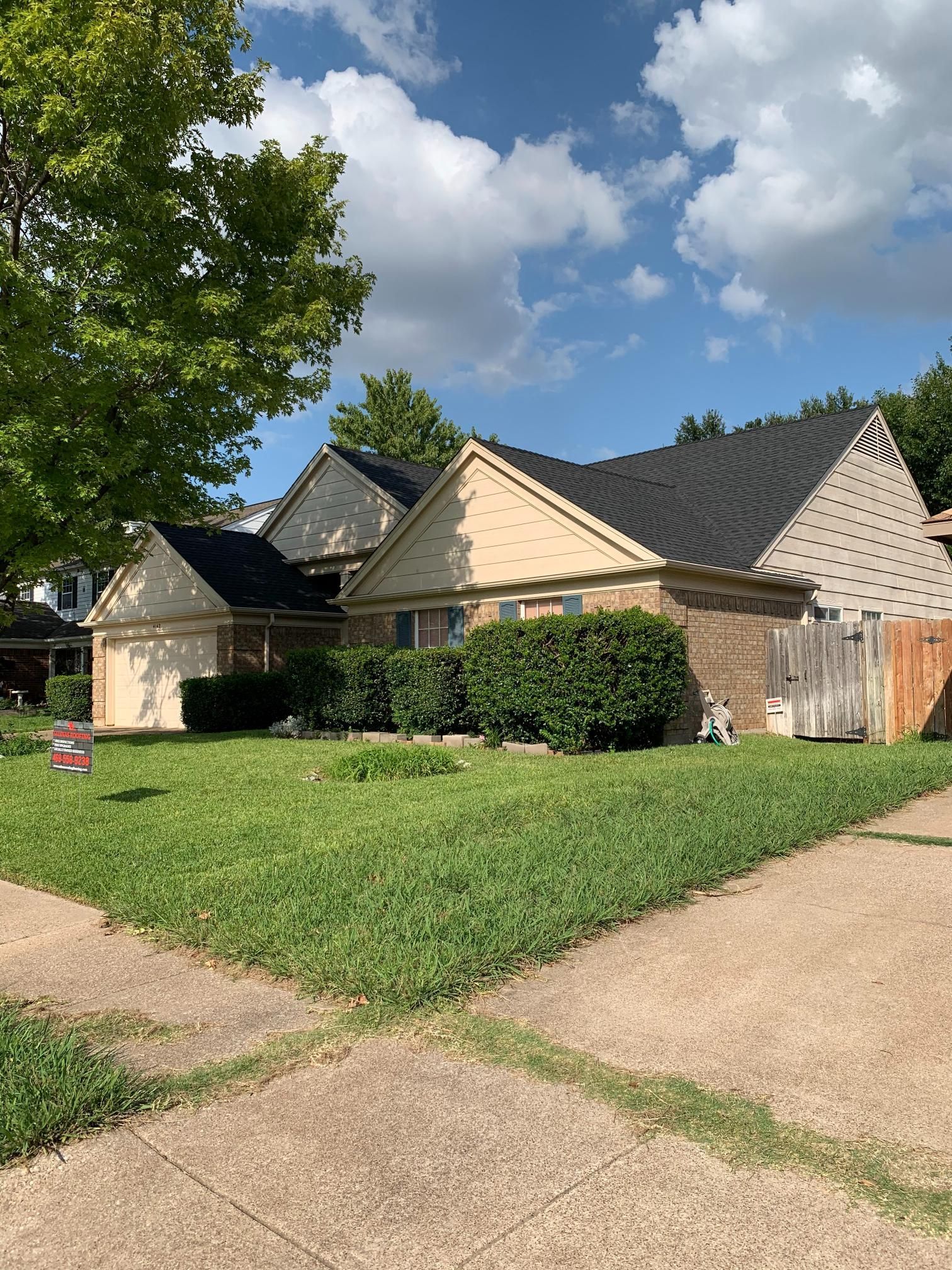 A house with a black roof is sitting on top of a lush green lawn.