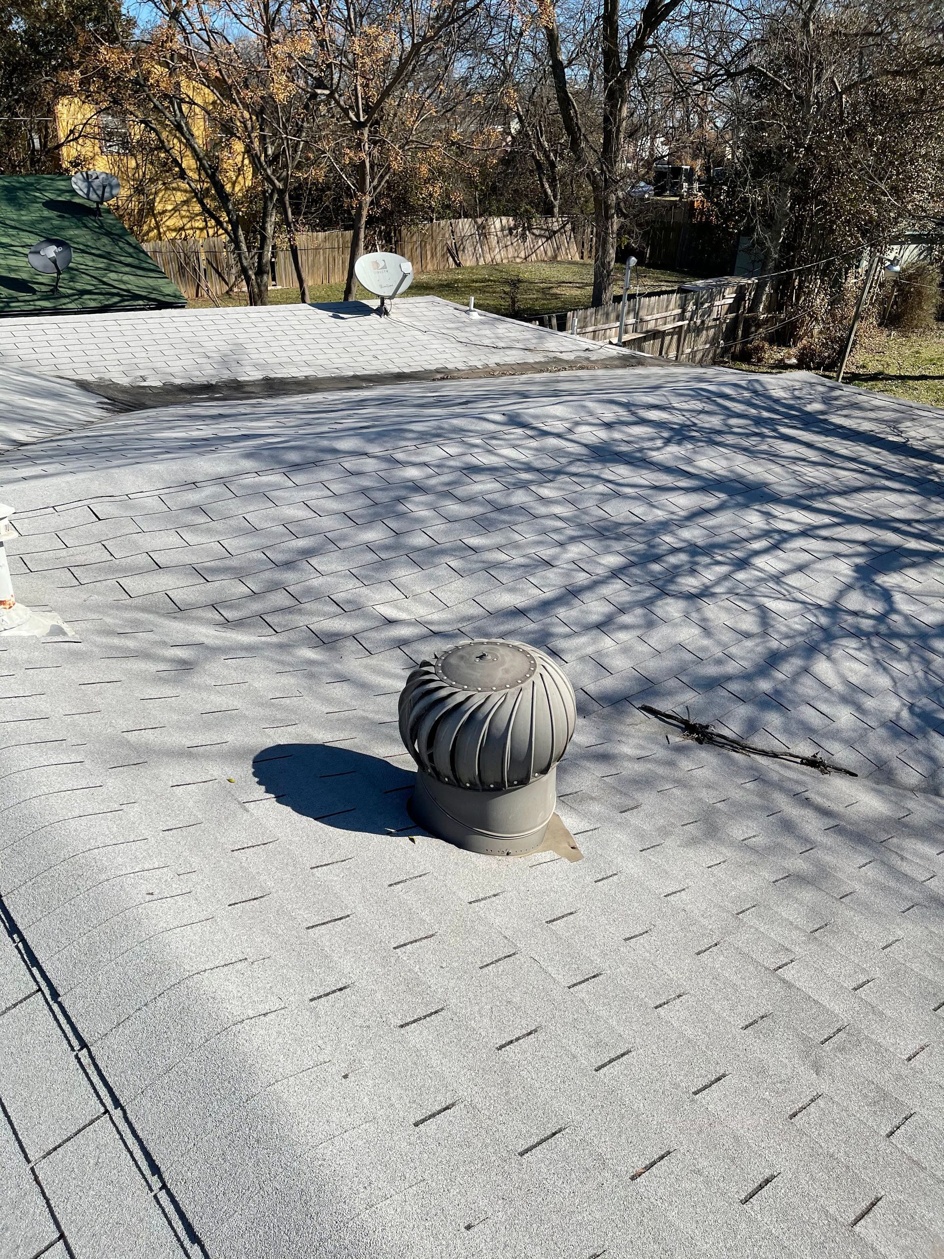 A roof with a chimney on it and trees in the background.