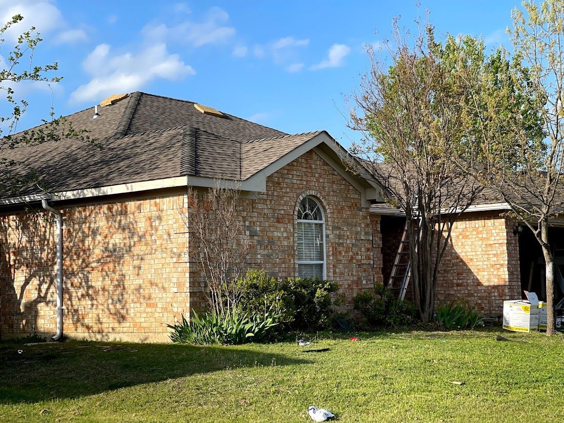 A brick house with a roof that has been damaged by a storm.
