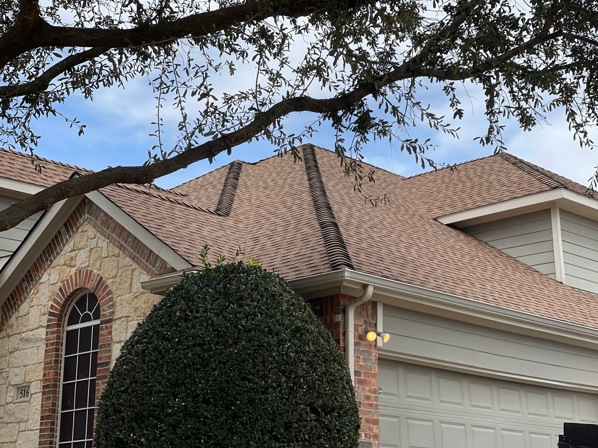 A house with a brown roof and a tree in front of it.