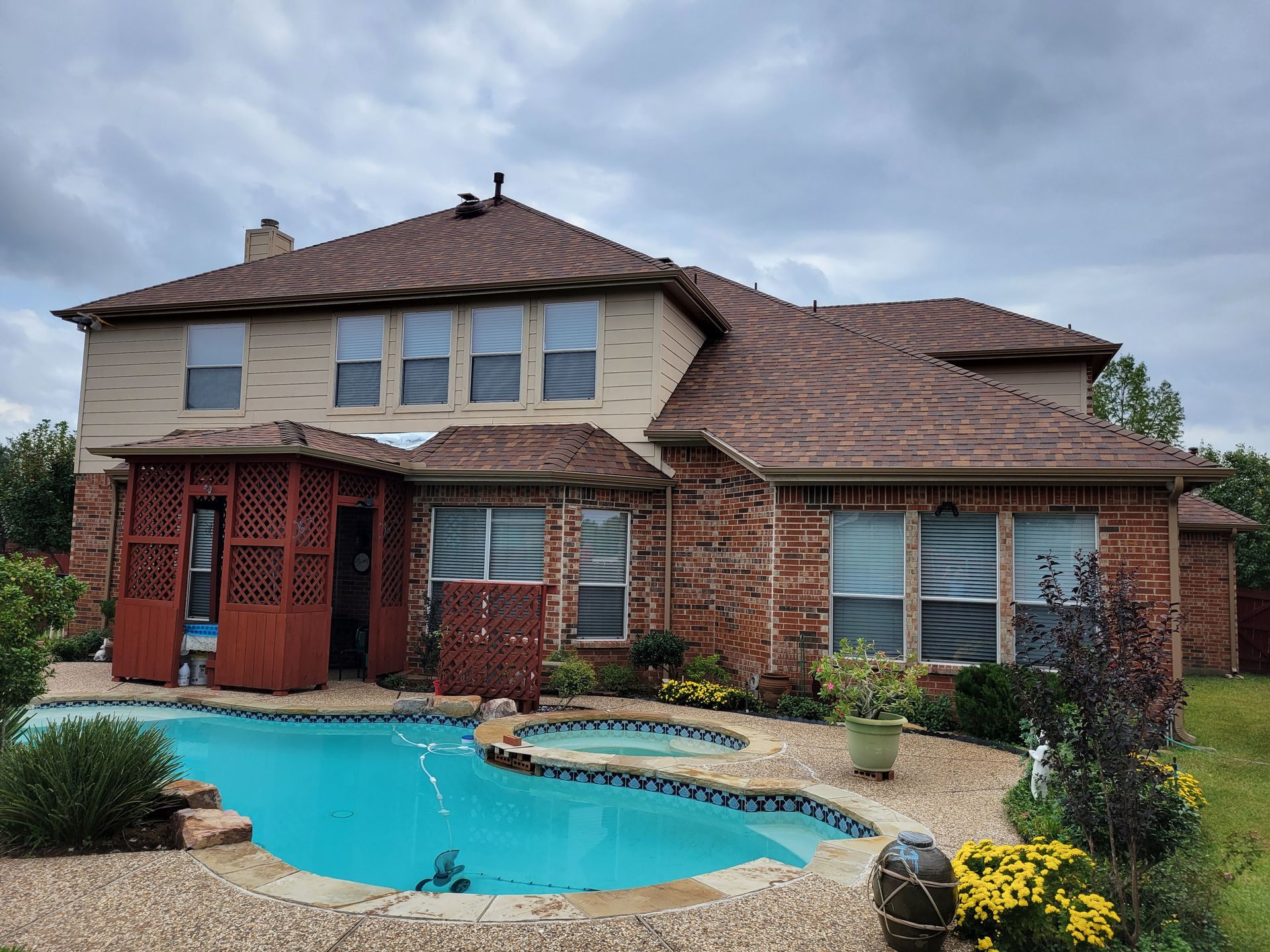 A large brick house with a swimming pool in front of it.