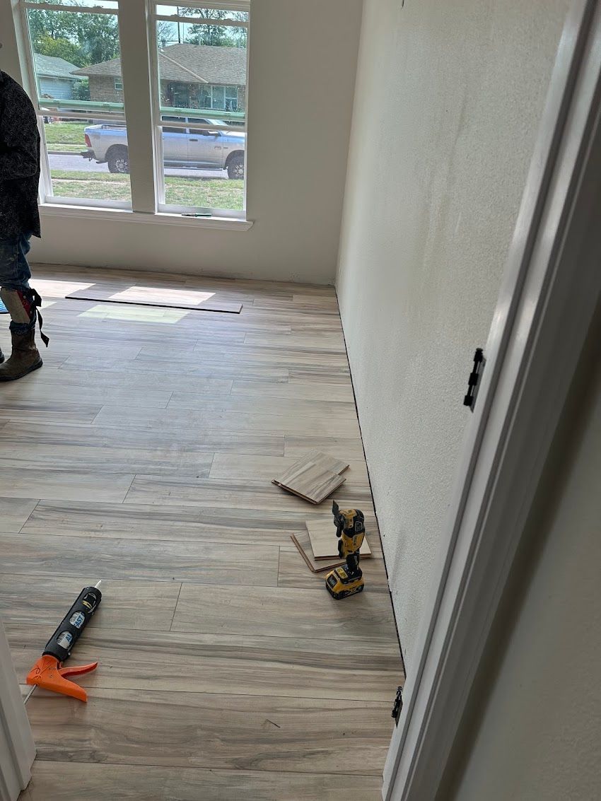 A man is standing in a room with a drill on the floor.