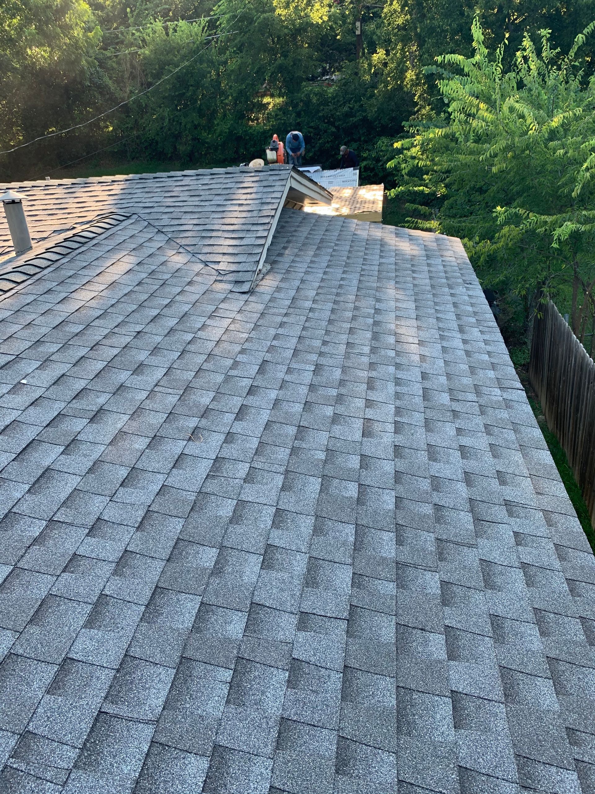 A roof with a lot of shingles on it and trees in the background.