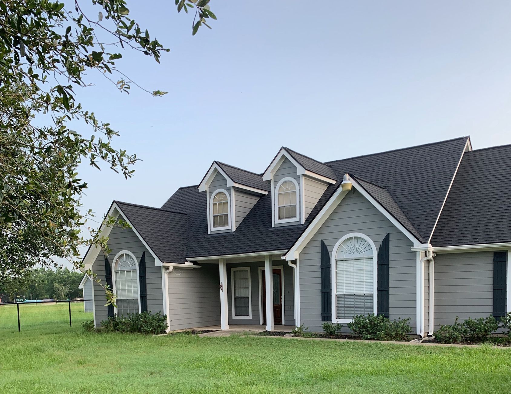 A large gray house with a black roof and black shutters