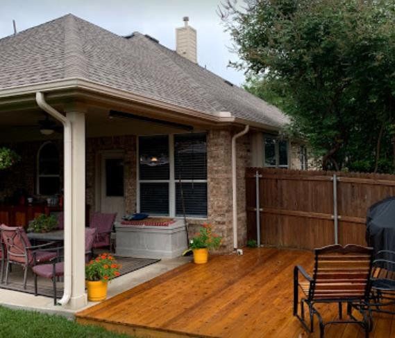 A house with a wooden deck and chairs in front of it.