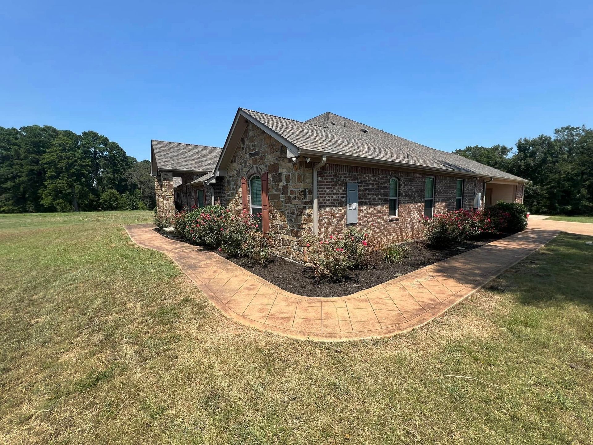 Brick building with dark roof and curved walkway, landscaping in front.