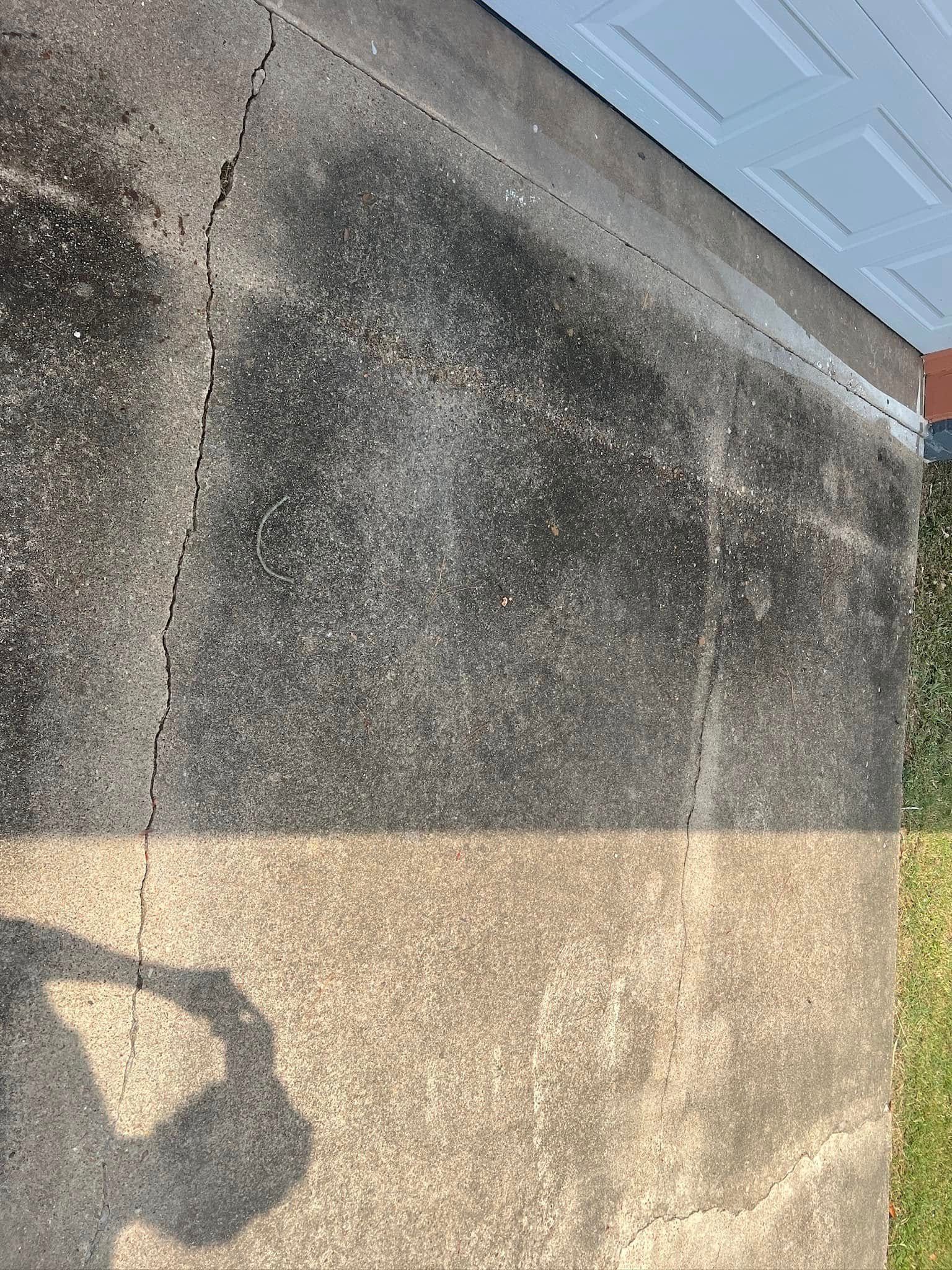 Dark stained concrete next to a white garage door and grass.