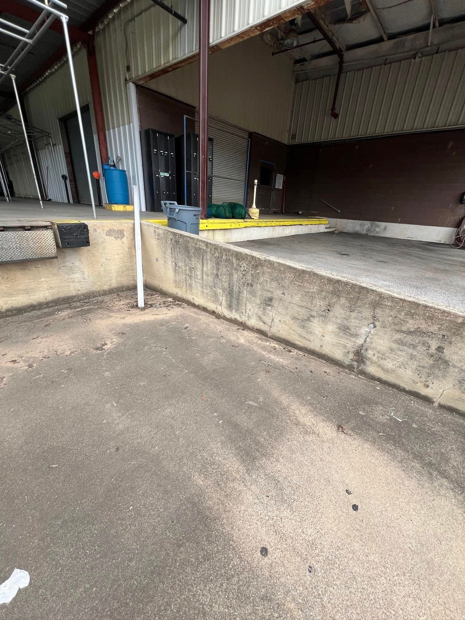 Concrete loading dock at a warehouse. Metal structures are visible in the background.