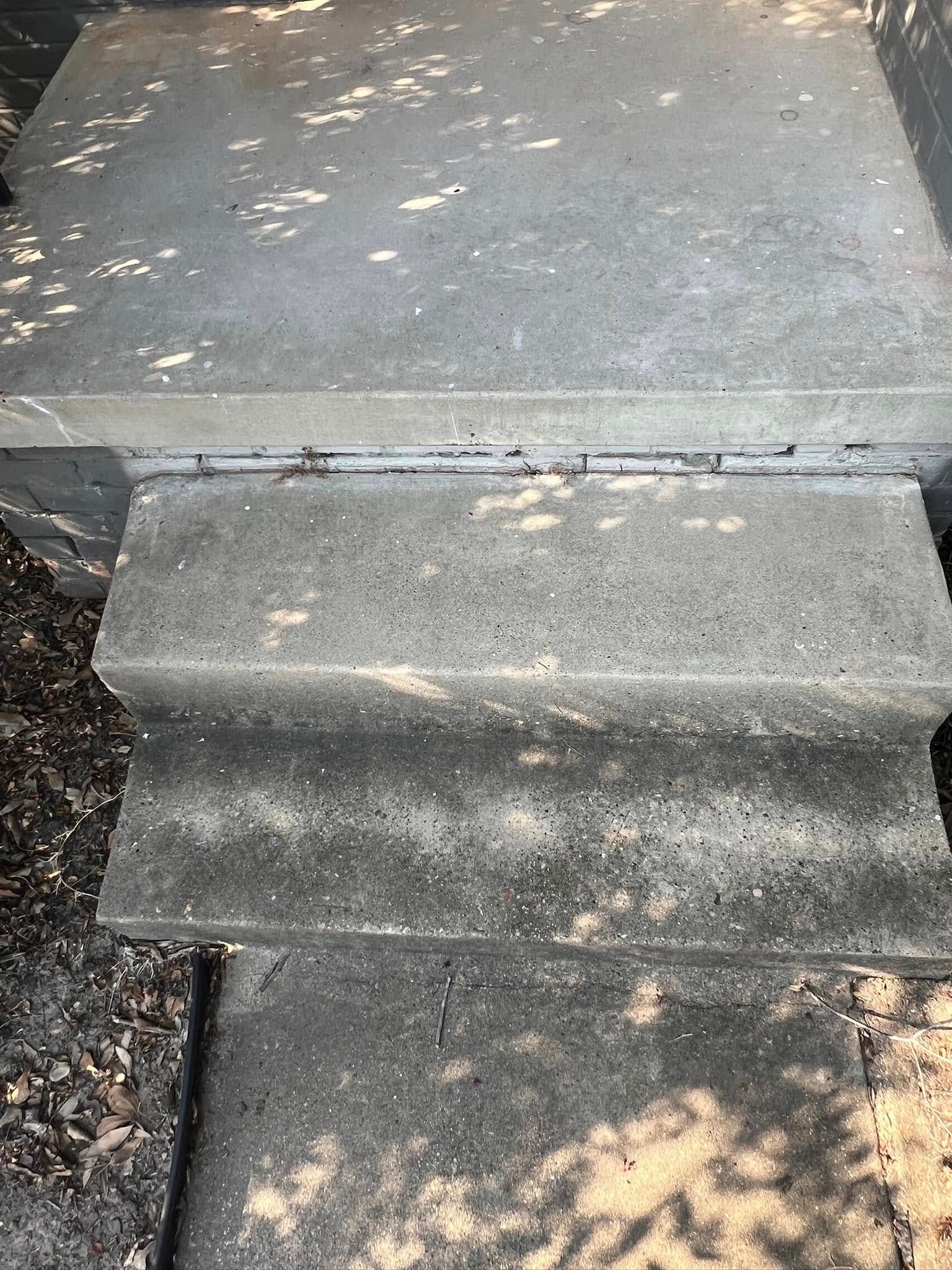 Concrete outdoor steps leading up to a landing. Sunlight creates shadows.