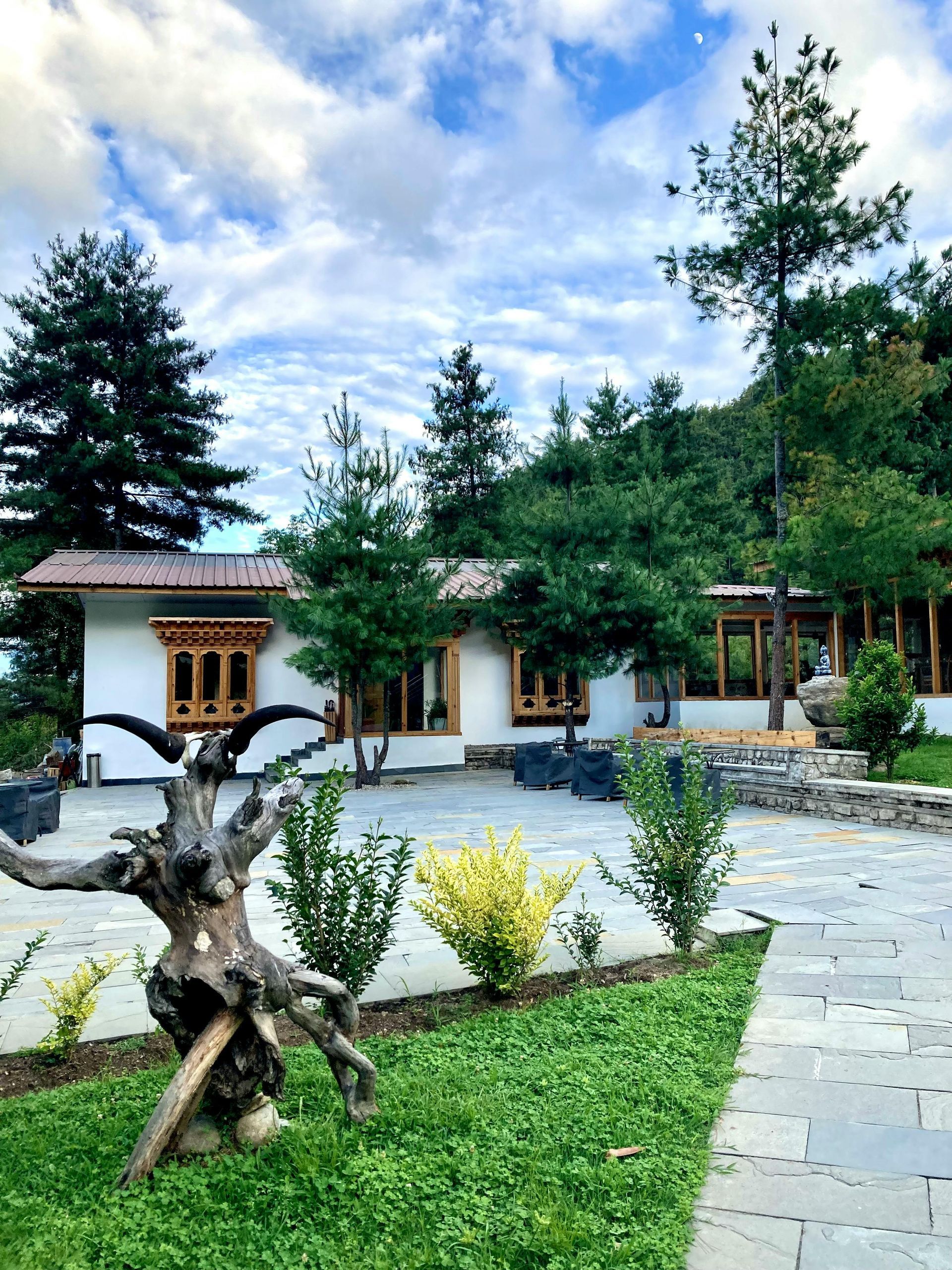 White building with wooden trim, trees, and stone pathway in Bhutan.