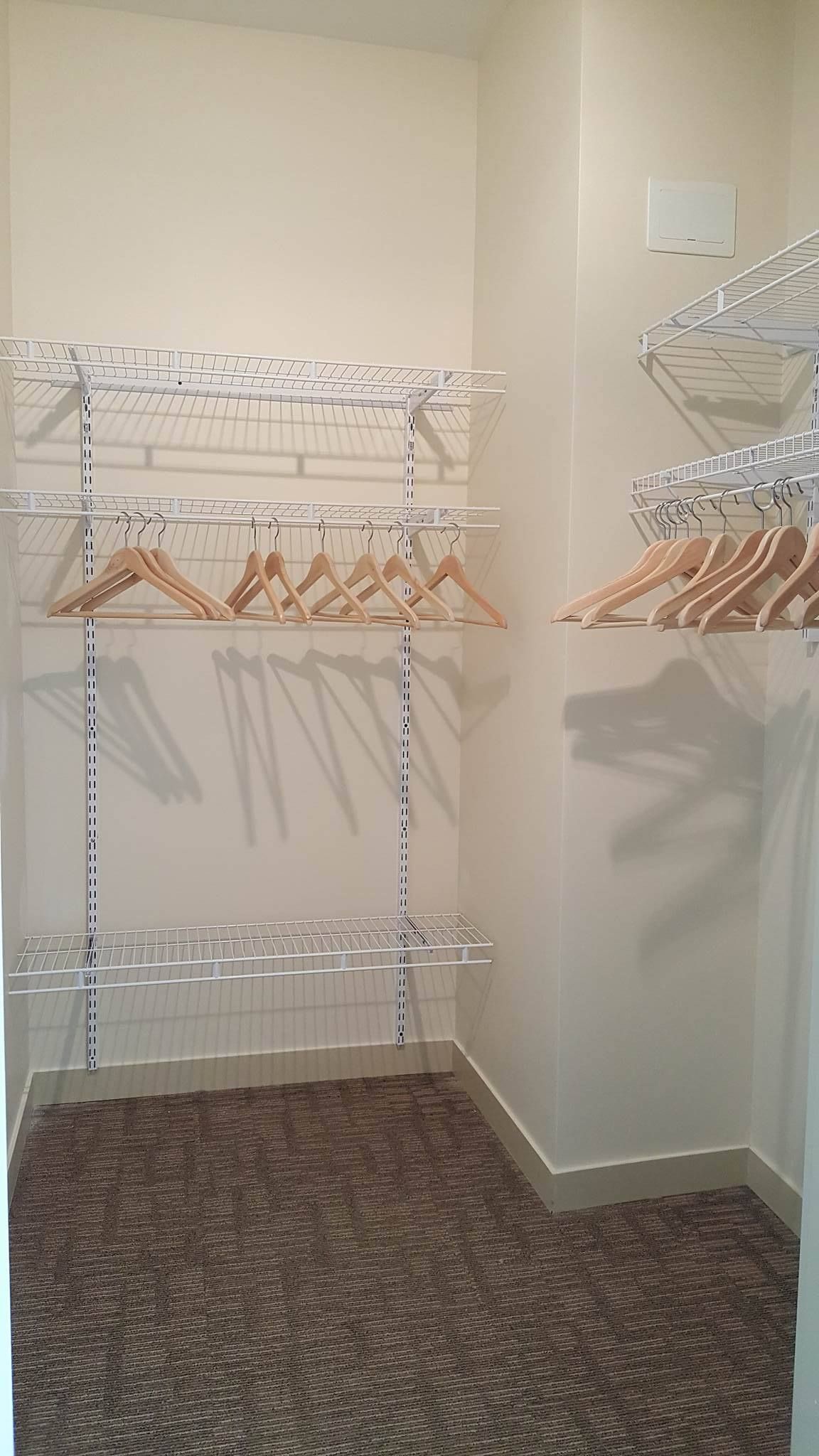 A walk in closet with a lot of clothes hanging on the racks.