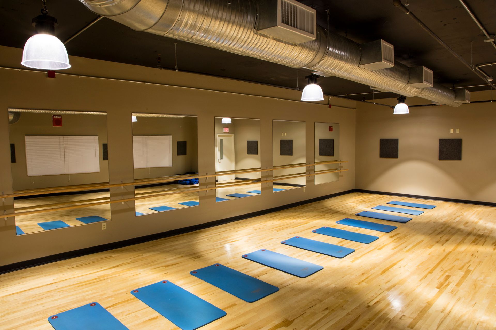 A large room with a lot of mirrors and blue mats on the floor