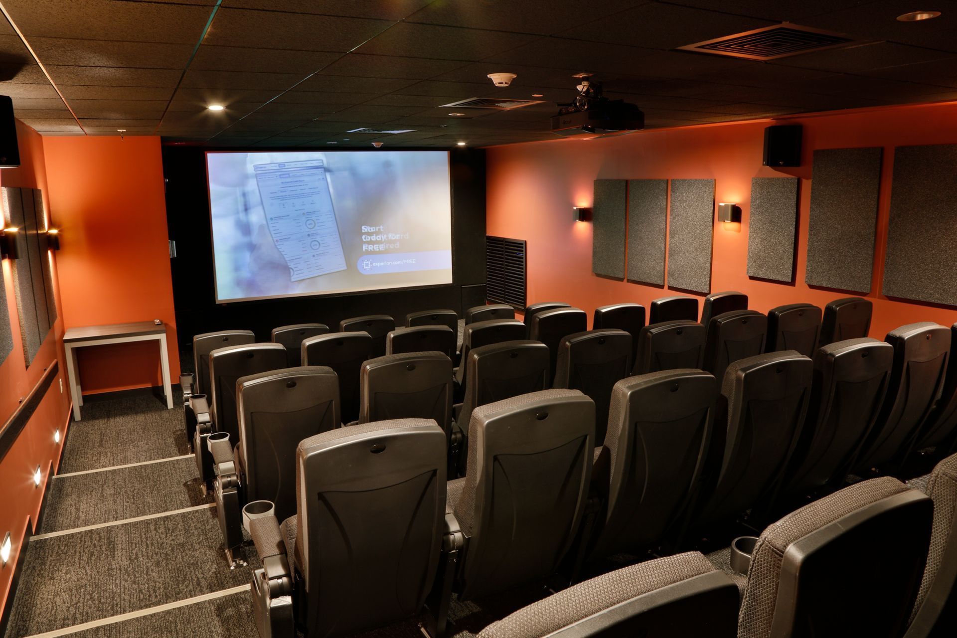 A movie theater with rows of seats and a large screen