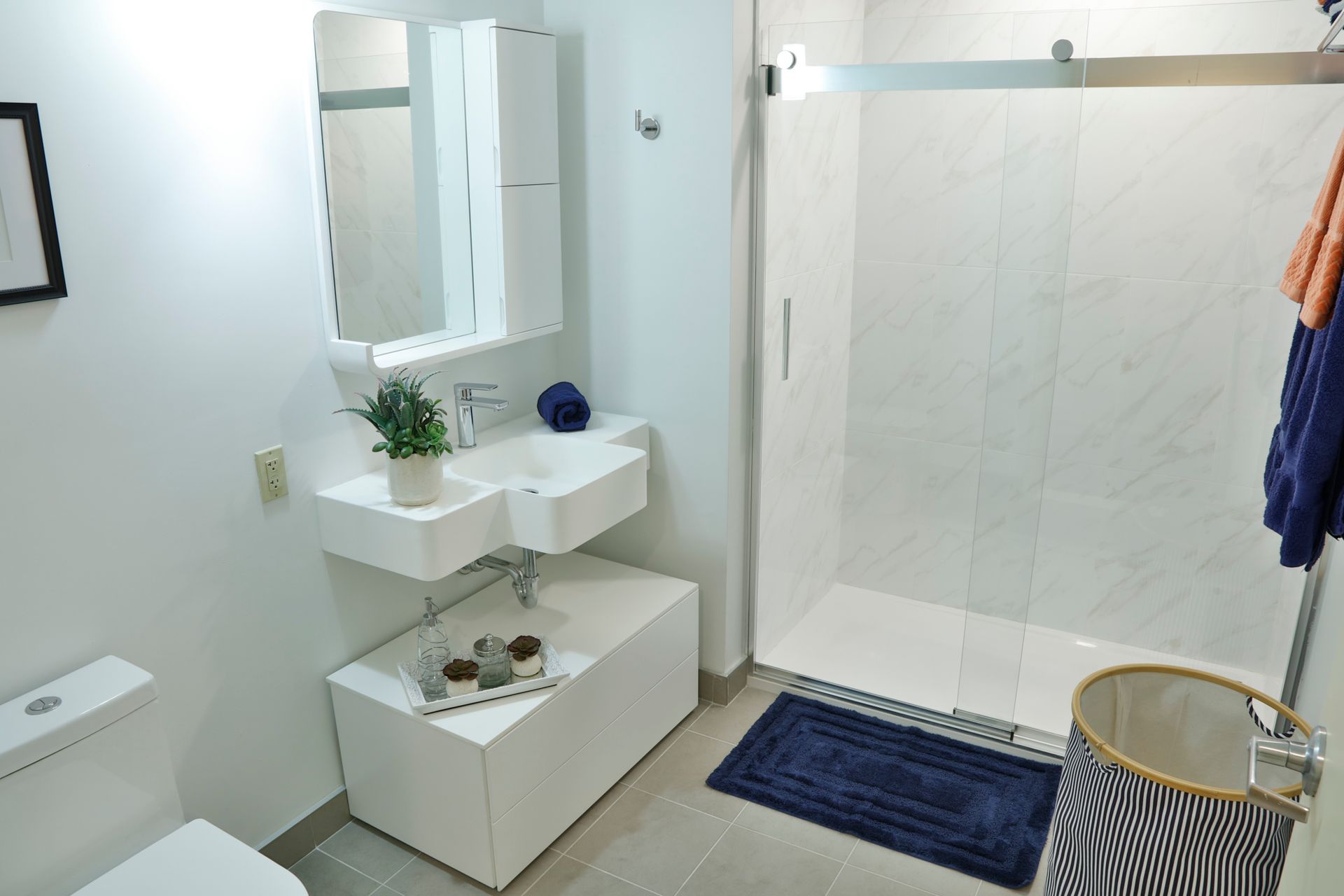 A bathroom with two sinks , a toilet , and a walk in shower.