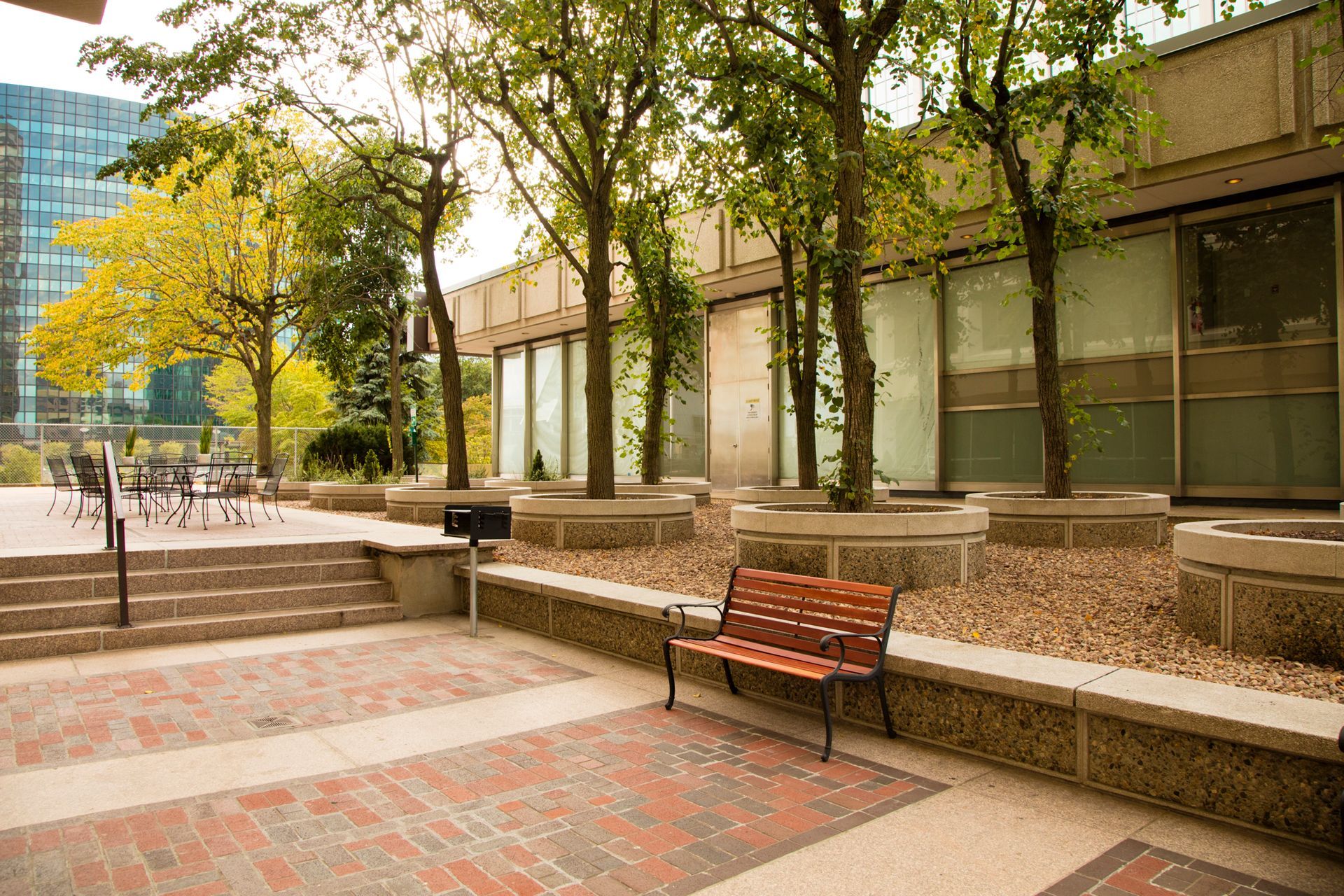 A wooden bench is sitting in front of a building surrounded by trees.