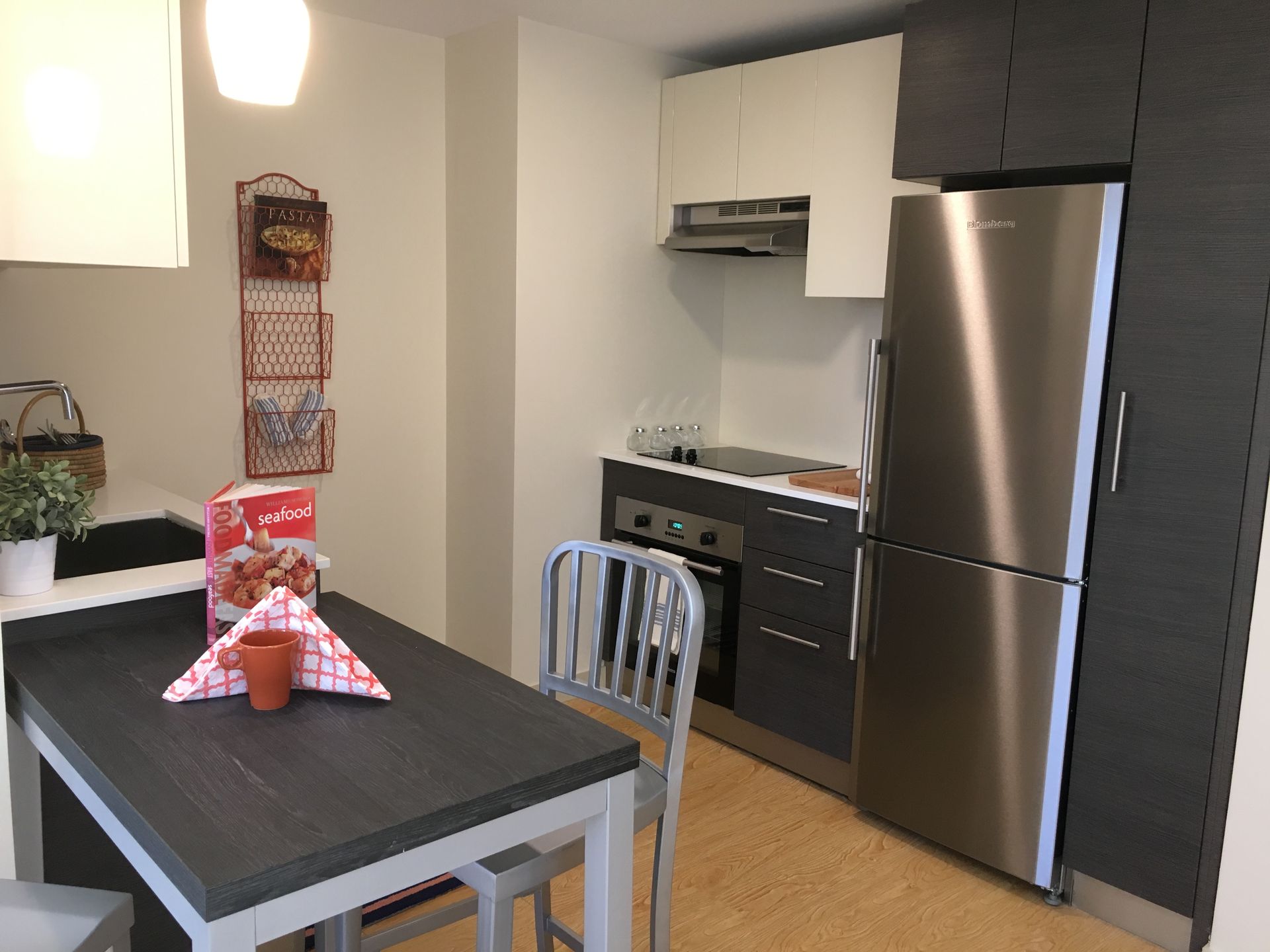 A kitchen with a table and chairs and a stainless steel refrigerator