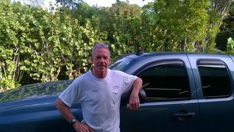 A man in a white shirt is leaning against a truck