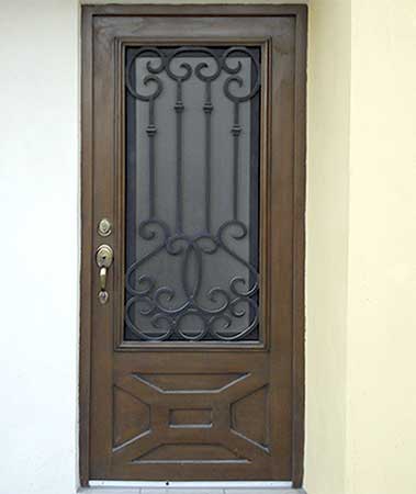 Una puerta de madera con una mampara de hierro forjado en una pared amarilla.