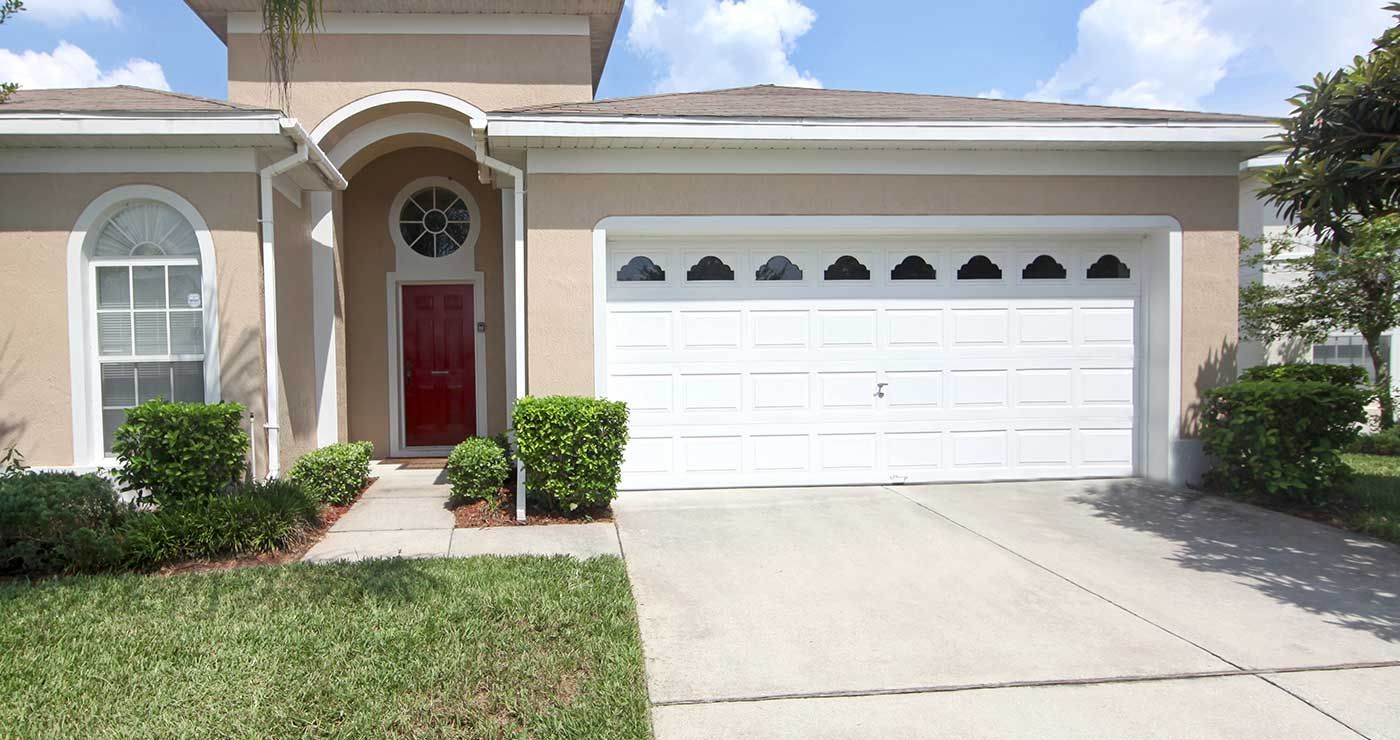 Una casa con una puerta de garaje blanca y una puerta roja.