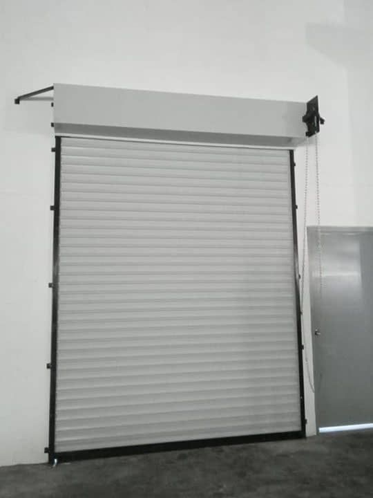 Una puerta de garaje enrollable blanca está abierta en un almacén.