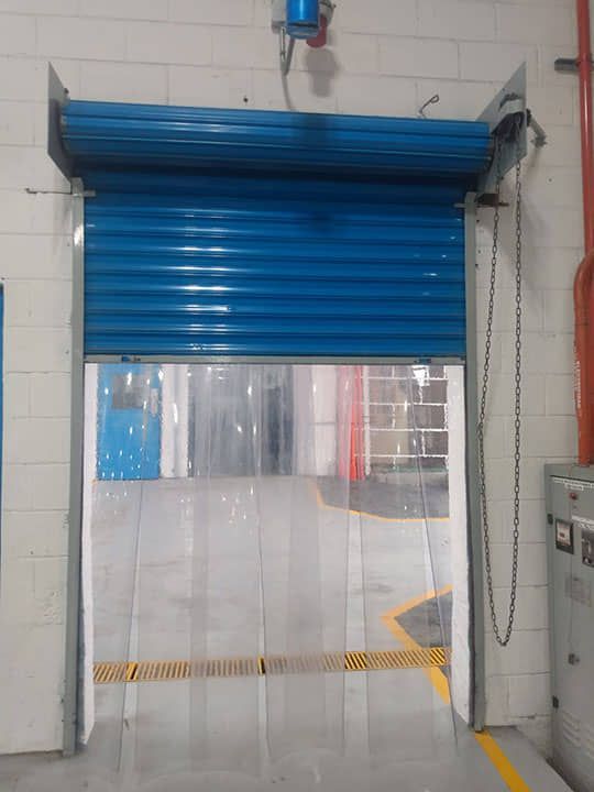 Una puerta enrollable azul está abierta en un almacén.