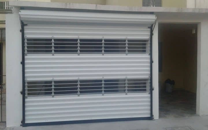 Una puerta de garaje blanca con un marco negro se encuentra frente a un edificio.