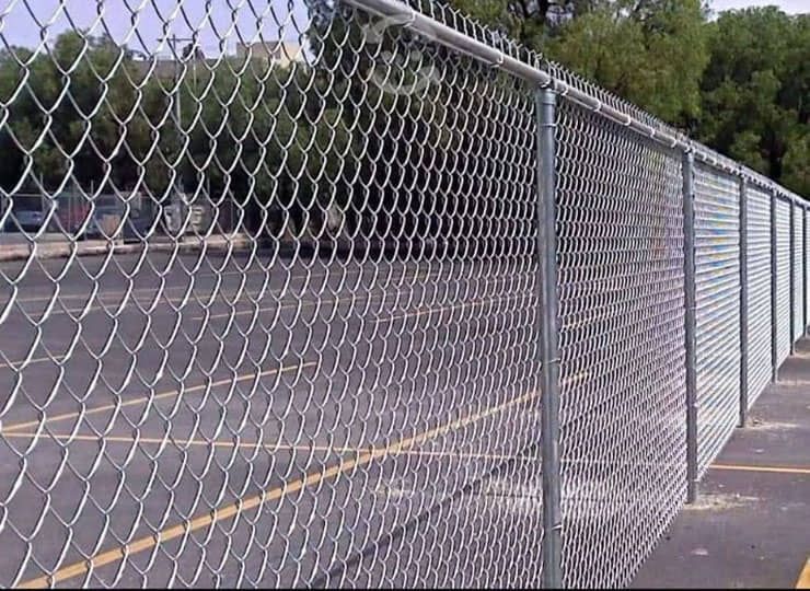 Una valla de alambre rodea un estacionamiento.