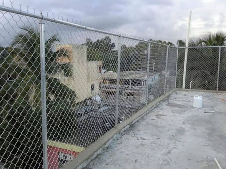 Una valla de alambre rodea un tejado con palmeras al fondo