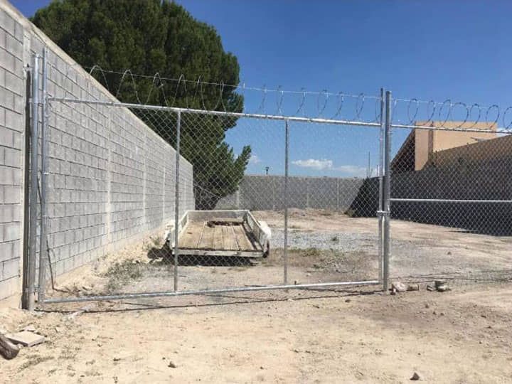 Un remolque está detrás de una valla de alambre de púas.