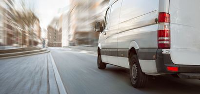 Una camioneta blanca circula por una calle de la ciudad.