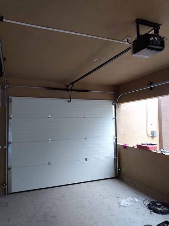 Un garaje con una puerta blanca y un abridor de puerta de garaje.