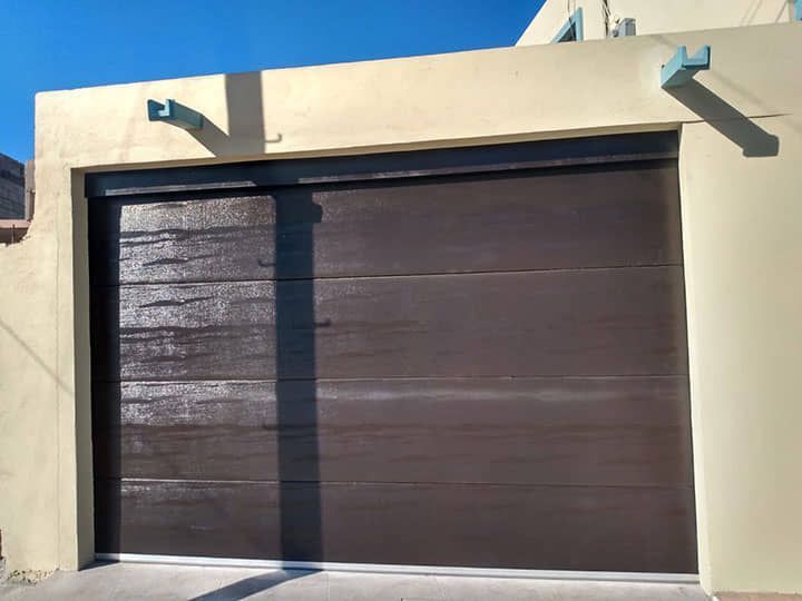 Una puerta de garaje marrón está en una pared blanca.