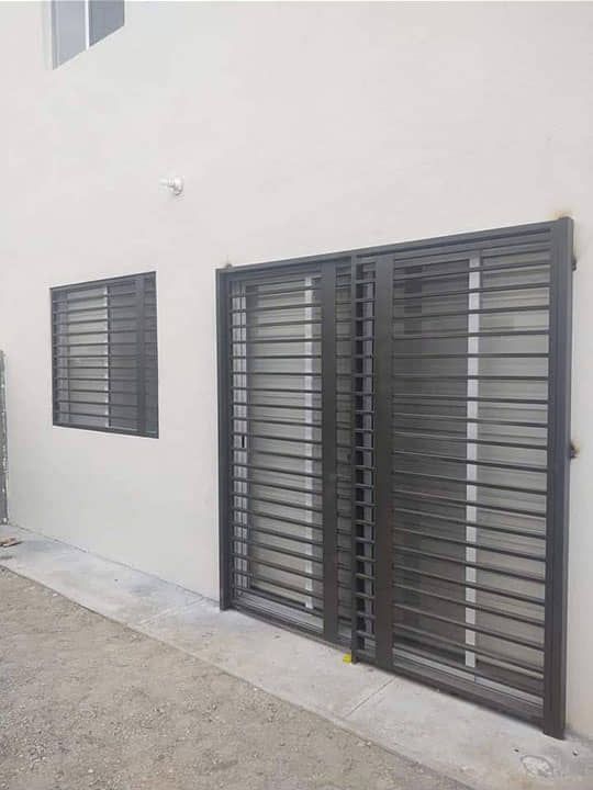 Un edificio blanco con una puerta de hierro forjado y dos ventanas.