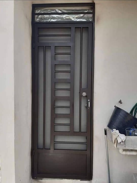 Una puerta de hierro forjado se encuentra sobre una pared blanca.