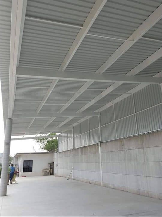 Un estacionamiento cubierto con techo blanco y pared de concreto.