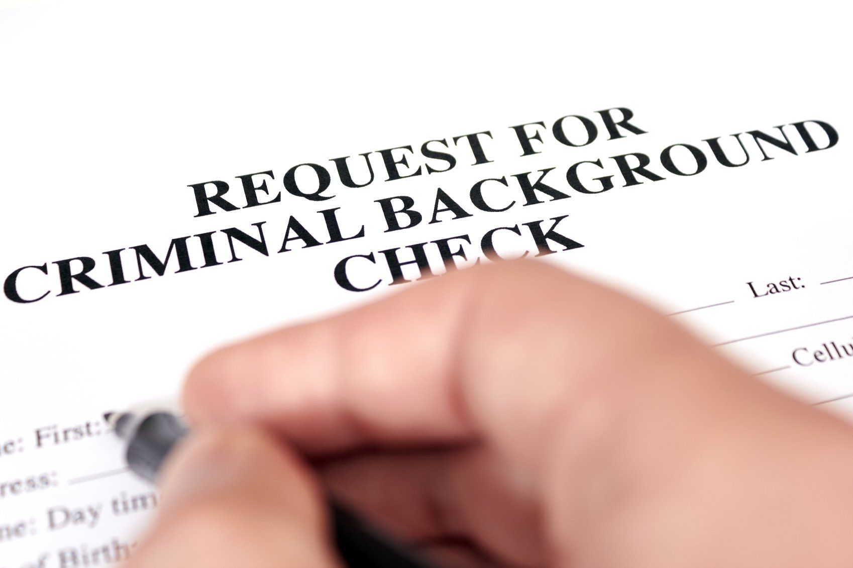 person writing on background check form