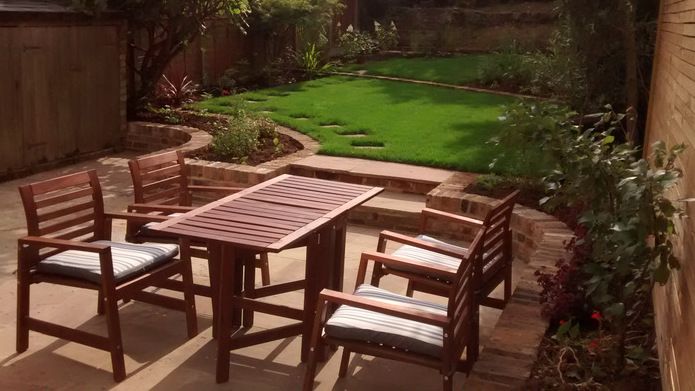 Dining table in foreground of large garden with terraced lawn