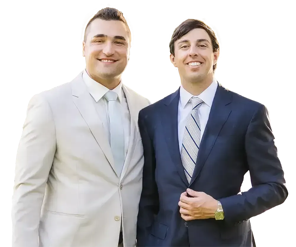 Two individuals in formal business suits smiling for a portrait against a white background.