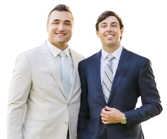 Two individuals in formal business suits smiling for a portrait against a white background.