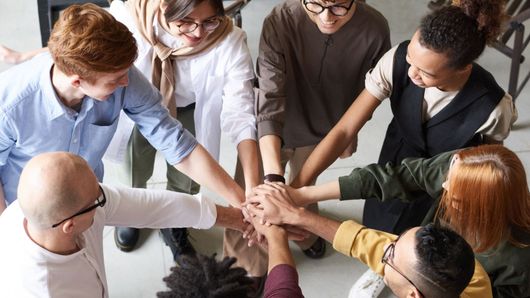 A group of people are putting their hands together in a circle.