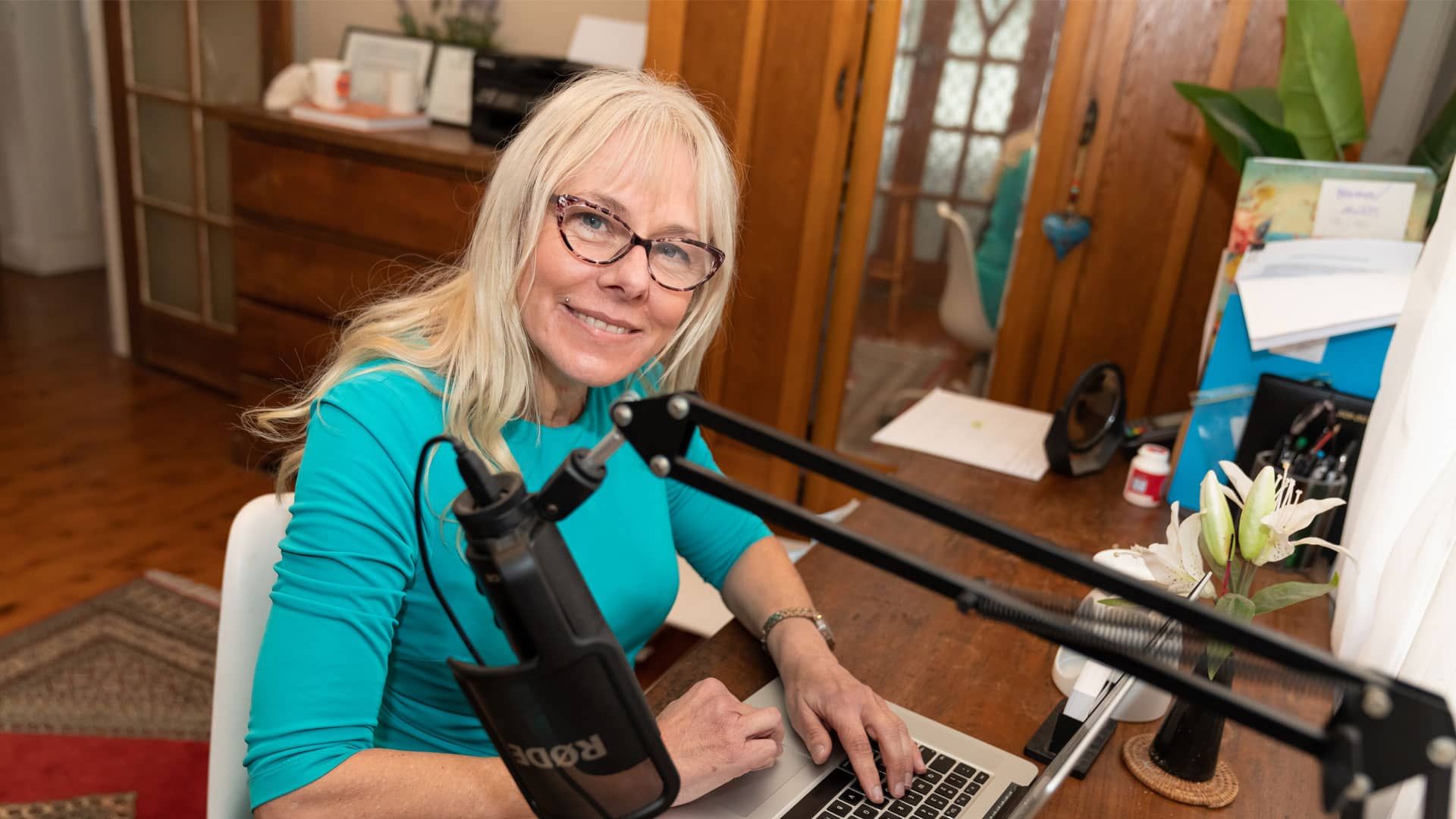 Toni Knight is sitting at a desk with a laptop and a microphone.