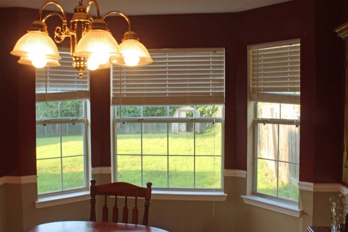 Bay window blinds in a dining room with ceiling lights on near at Harmony Blinds & Shutters near San Diego, CA