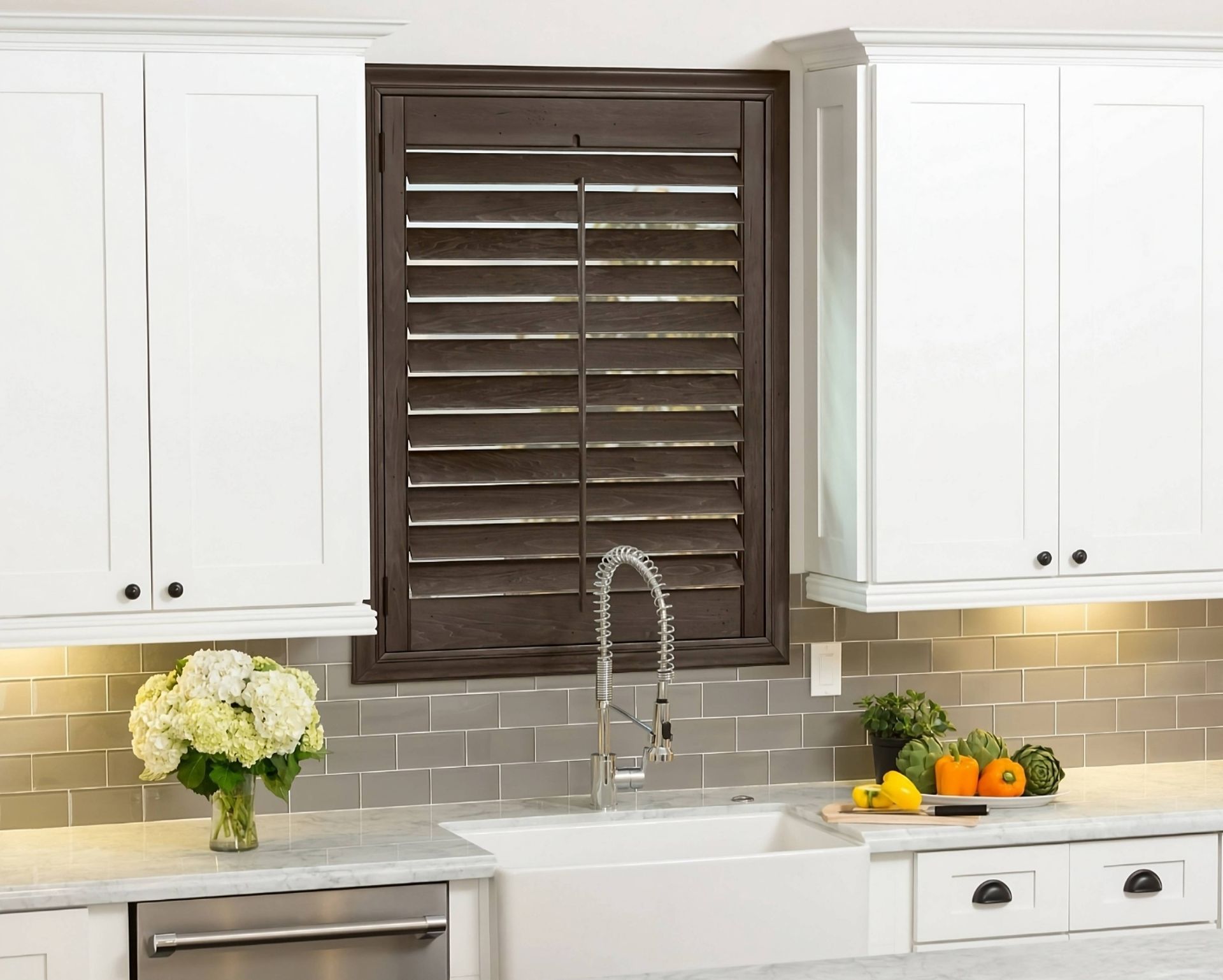 Dark wood Hunter Douglas Heritance® Wood Shutters on a window above a kitchen sink at Harmony Blinds & Shutters near San Diego, CA
