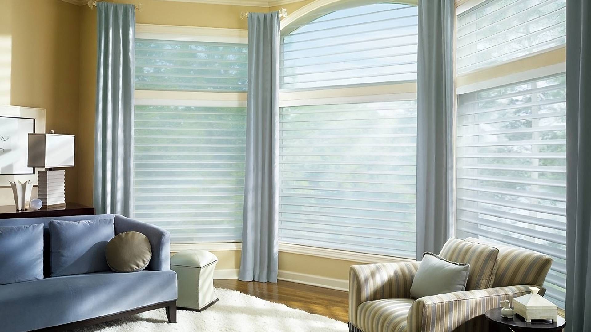 Warm living with large arched windows with luxurious window coverings at Harmony Blinds & Shutters n