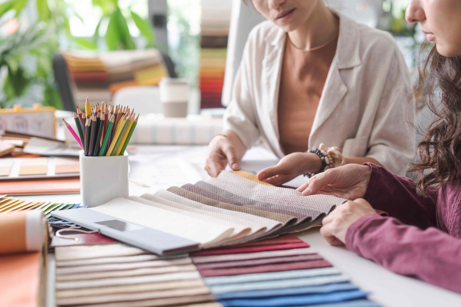  window fashions expert collaborating with a client on selecting fabric swatches for custom window treatments at Harmony Blinds & Shutters near San Diego, CA