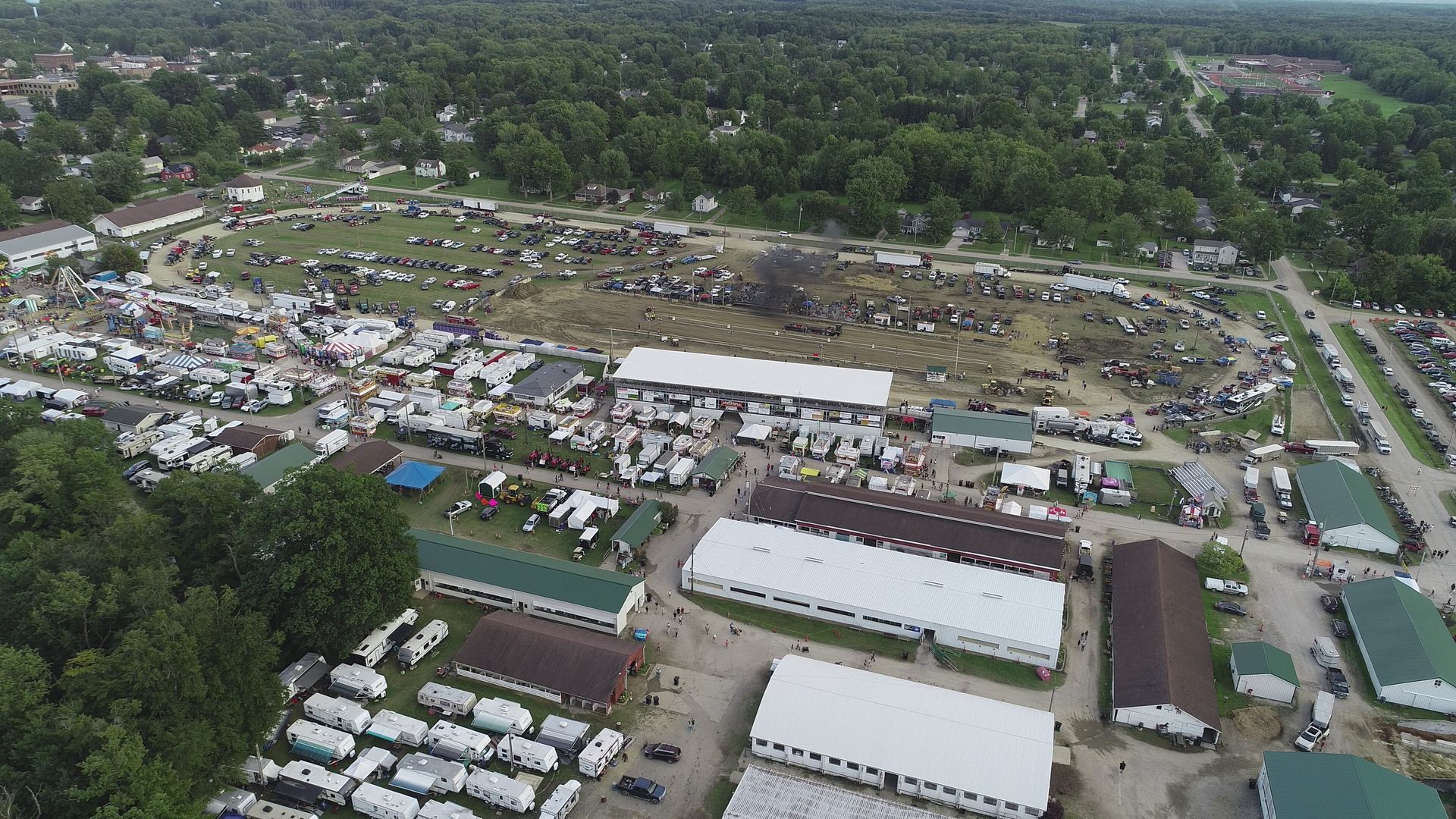 People browsing a flea market, focusing on a person wearing a straw hat standing near a knife block set.