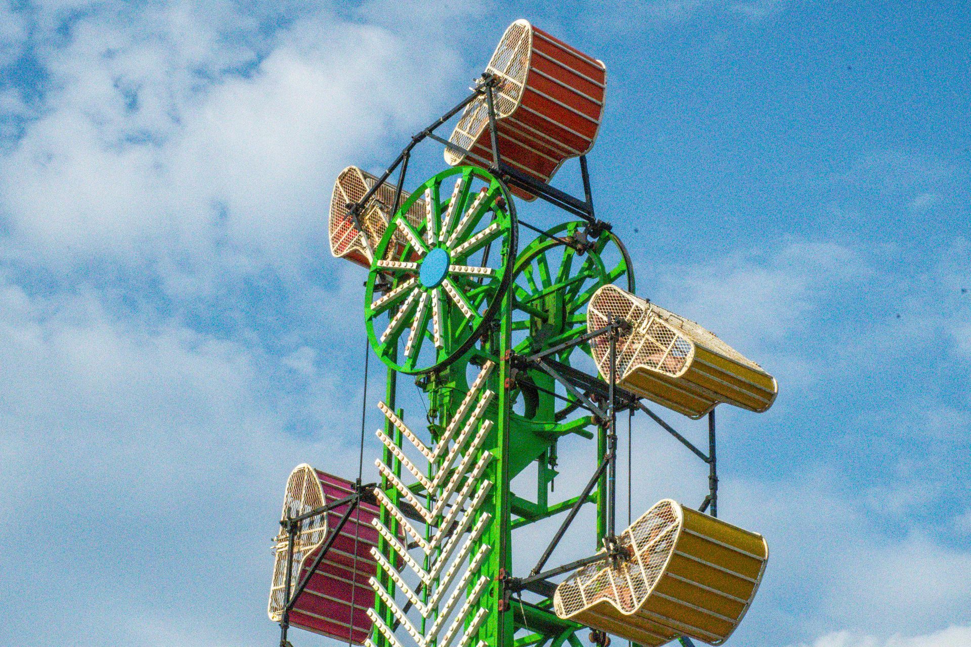 An indoor event space featuring rows of tables with blue and green cloths, chairs, and people attending a community fair.