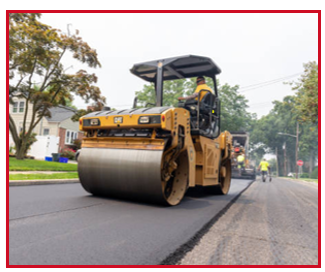 A man is driving a roller on a road.