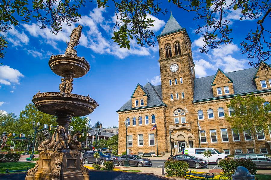 A large building with a clock tower and a fountain in front of it