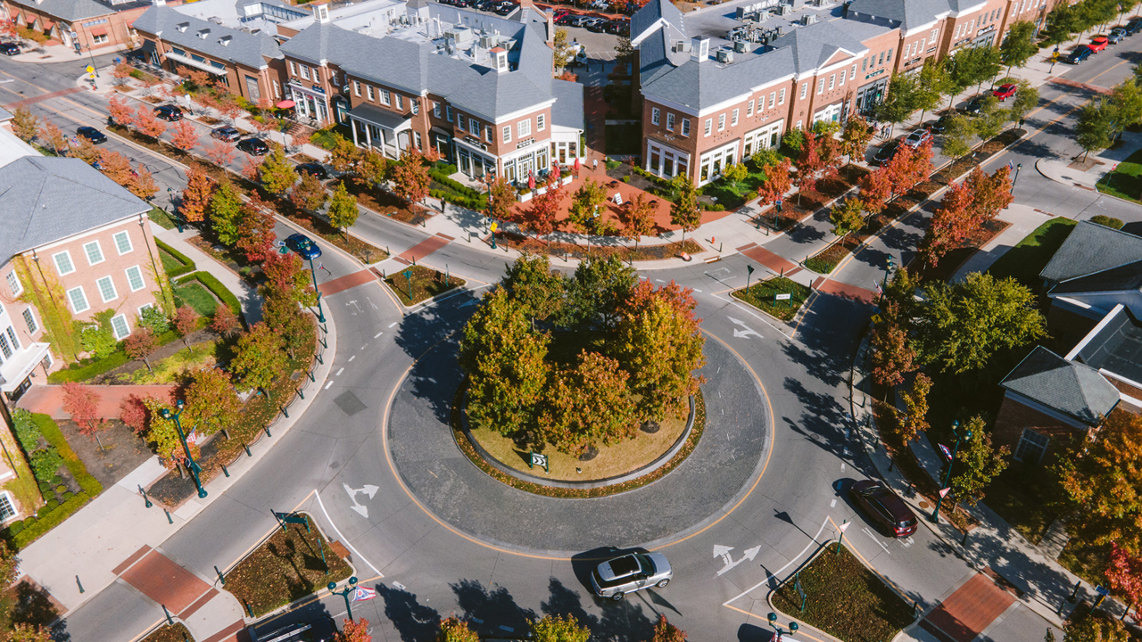 An aerial view of a roundabout in a city with buildings in the background.